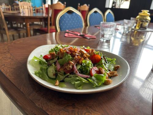 ein Salat auf einem weißen Teller auf einem Holztisch in der Unterkunft Studlagil INN Hostel in Skjöldólfsstaðir