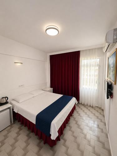 a bedroom with a large bed and a red curtain at Soykan Hotel in Marmaris