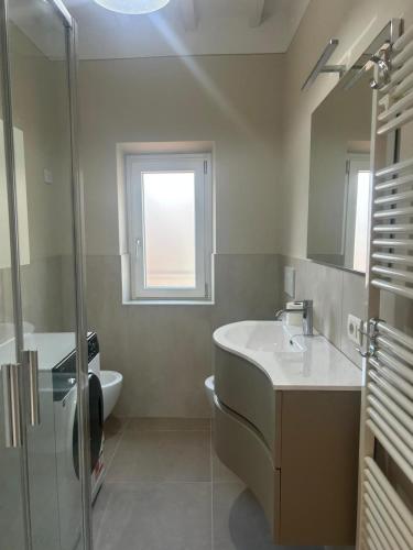 a bathroom with a sink and a toilet and a window at San Leo Apartment in Stia
