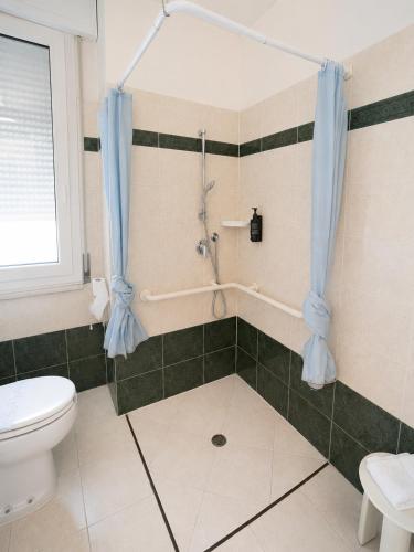 a bathroom with a toilet and a shower with blue curtains at Hotel Italia in Ravenna