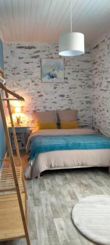 a bedroom with a bed and a stone wall at Entre vigne et Loire in La Coindassière