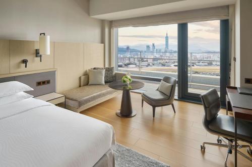 a hotel room with a bed and a couch and a window at Taipei Marriott Hotel in Taipei