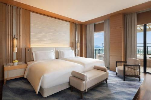 a bedroom with a large white bed and a chair at The Ritz-Carlton Okinawa in Nago