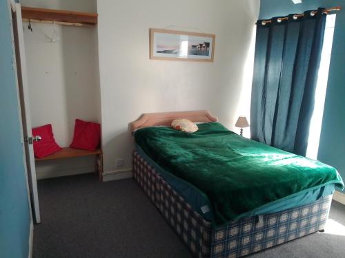a small bedroom with a bed with a green comforter at House near beach in Port Talbot
