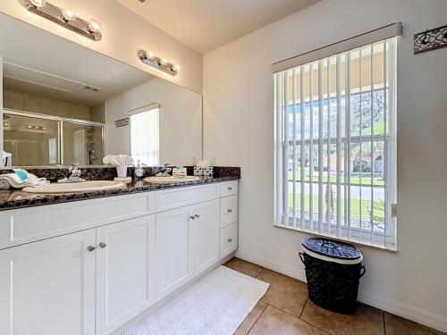 a white bathroom with two sinks and a window at 3BR Home Trailside Pool & Jacuzzi, Minutes from Inverness, Ocala & Crystal River in Inverness