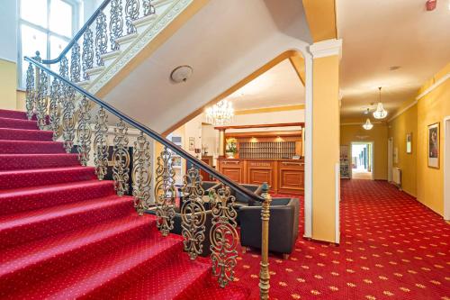 a staircase with red carpet and a suitcase on it at Hotel Luisa in Františkovy Lázně