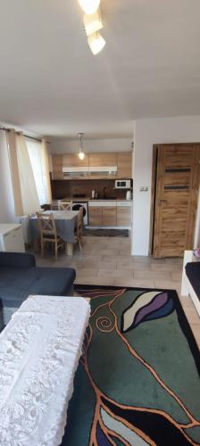 a living room with a table and a kitchen at Apartament Przylesie 2 in Stężyca