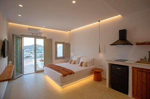 a bedroom with a bed and a kitchen with a window at Stilvi Mykonos in Ornos