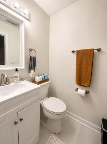 a white bathroom with a toilet and a sink at Modern Main Street Charm in Georgetown