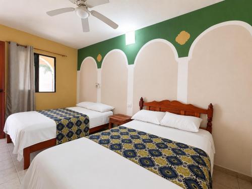 two beds in a room with green and white walls at Hotel Santa Ana in Valladolid