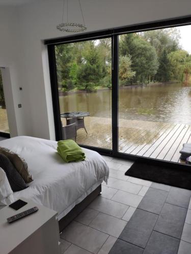 a bedroom with a large window with a view of a river at Egret Woody Park in Willand