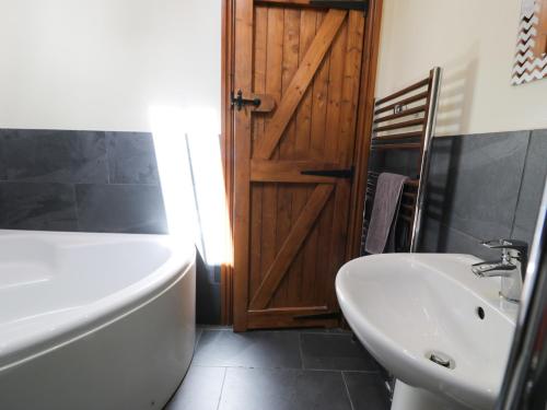 a bathroom with a tub and a sink next to a door at Cornel Clyd in Llanddulas