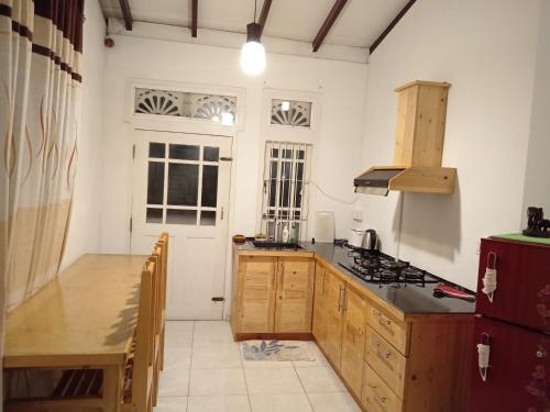 a kitchen with wooden cabinets and a counter top at Sobasee Holiday Bungalow in Kandy