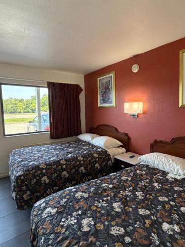 a hotel room with two beds and a window at Travel Inn in Greensboro