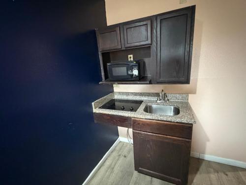 a kitchen with a sink and a microwave at Paradise Inn & Suites in Baton Rouge