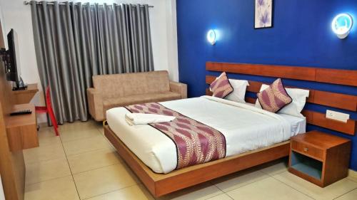 a bedroom with a bed and a chair at Hotel Wayanad Gate in Wayanad