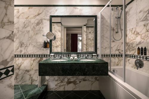 a bathroom with a green sink and a mirror at Sina De La Ville in Milan