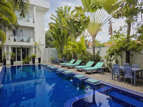 a swimming pool with chairs and a building at Angkor Sweet Night Hotel in Siem Reap