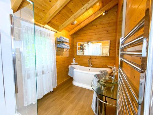 a bathroom with a tub and a glass table at Kingfishers Woody Park in Willand