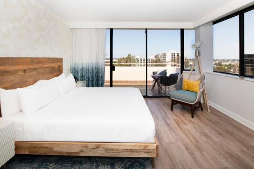 a bedroom with a bed and a chair and windows at Renaissance Newport Beach Hotel in Newport Beach