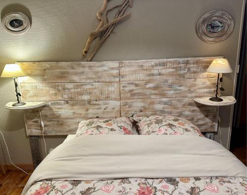 a bedroom with a wooden headboard and two lamps at B&B Le Rupicapra in Roubion