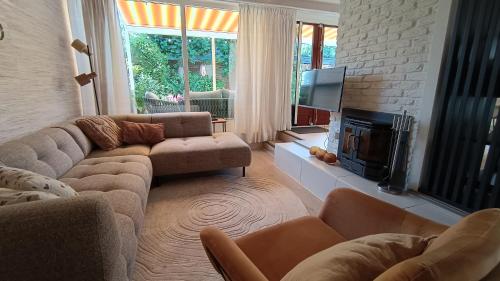 a living room with couches and a tv and a fireplace at Vakantiehuis Lycka in Noordwijkerhout