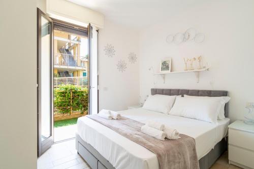 a white bedroom with a large bed and a window at Pepita del Lago - Piscina e Parcheggio privato in Lenno