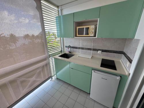 a small kitchen with a sink and a microwave at Ti Dyaman - Studio vue mer & accès piscine gratuit in Le Diamant