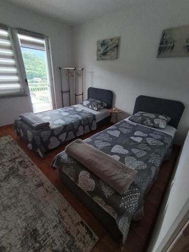 two beds sitting in a room with a window at Vikend kuća Konjic in Konjic