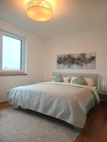 a bedroom with a large white bed with a large window at Exclusive Apartment mit Alpenpanorama in Peiting