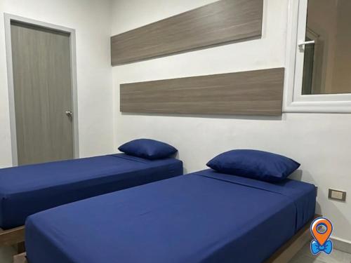 two beds in a room with blue pillows at Depa Amplio Vista al Mar Cerca del Malecón in Mazatlán