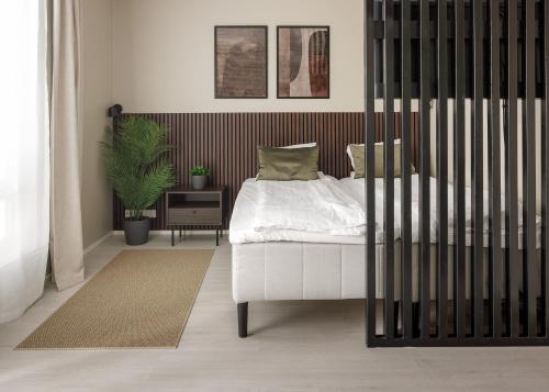 a bedroom with a white bed and a black fence at Calm Design Studio with Balcony & Parking in Pori