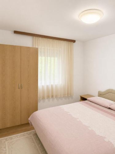a bedroom with a large bed and a window at Apartman Suzana in Šušanj