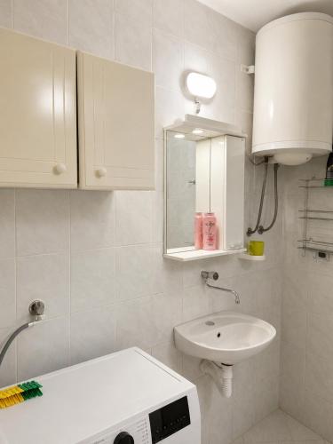 a white bathroom with a sink and a mirror at Apartman Suzana in Šušanj