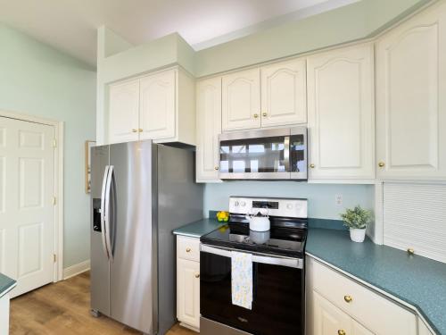 a kitchen with white cabinets and a stainless steel refrigerator at Oceanfront/Zero Steps to Beach/Views/4BR in Gulf Shores