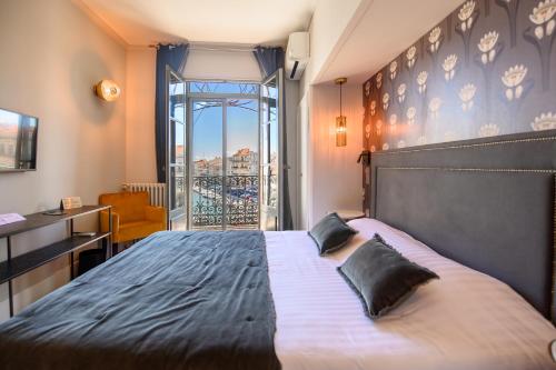 a bedroom with a large bed and a balcony at Le Grand Hotel in Sète