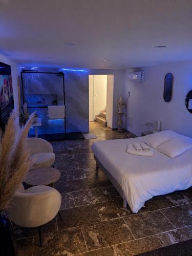 a bedroom with a large white bed and chairs at Suite avec jacuzzi DOLCE NOTTE in Rochegude