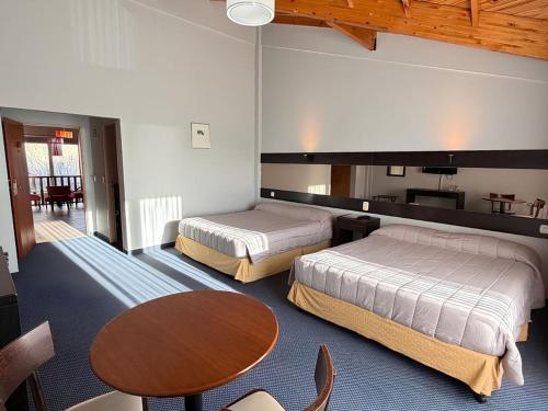 a hotel room with two beds and a table at Marcopolo Suites Calafate in El Calafate