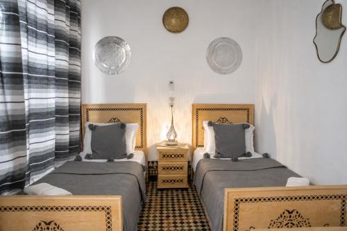 two twin beds in a room with two lamps at Riad Chada Fez in Fez