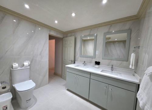 a bathroom with a toilet and a sink and mirror at Mistle Cove 102 in Christ Church