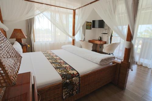 a bedroom with a canopy bed with a desk and window at Villa Dahl Beach Resort in Dar es Salaam