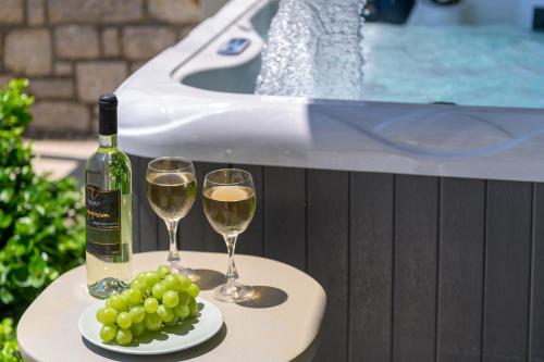 a table with two glasses of wine and a plate of grapes at Sirin Luxury Suites Groundfloor in Haraki