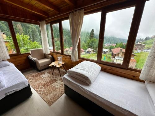 a bedroom with a bed and a chair and windows at Ayder Serender Otel in Çamlıhemşin