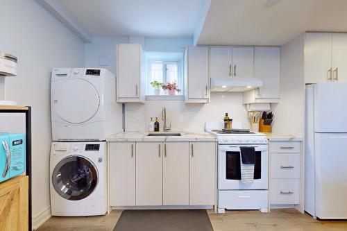 a kitchen with white cabinets and a washer and dryer at New & Modern Basement Suite - St Clair Hotel in Toronto
