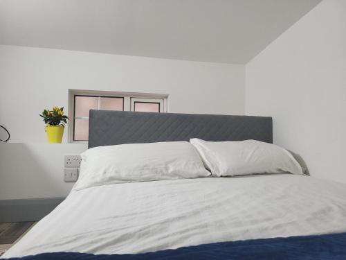 a bed with white sheets and a gray headboard at Historic Loft in Cork in Cork