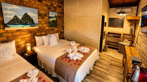 a bedroom with two beds with flowers on a table at Pousada Mar Aberto in Fernando de Noronha