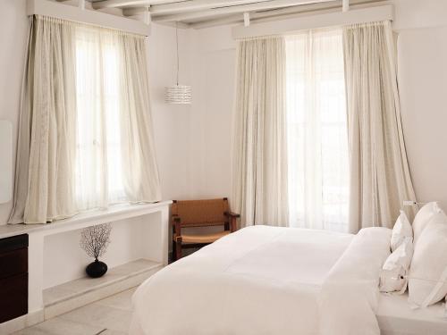 a white bedroom with a bed and a window at Belvedere Mykonos - Main Hotel - The Leading Hotels of the World in Mikonos