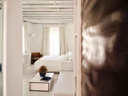 a white bedroom with a bed and a table at Belvedere Mykonos - Main Hotel - The Leading Hotels of the World in Mikonos