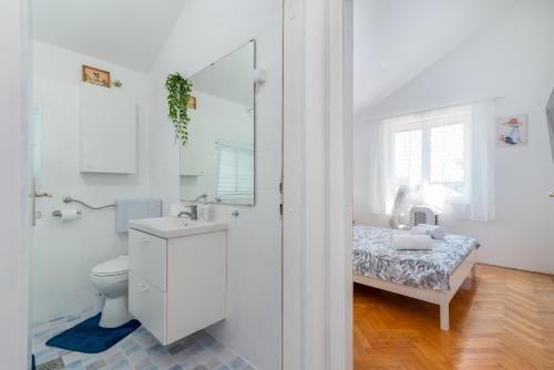 a white bathroom with a sink and a toilet at Guest house Bella in Slatine