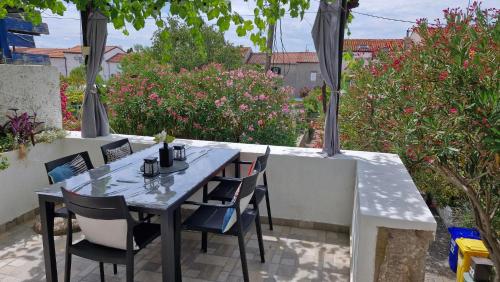 a table and chairs on a patio with flowers at Apartman Mocic in Punat